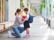 Why Do Americans Think Their Kids Need So Much Extra Help from Their Moms? first day at school. mother leads a little child school girl in first grade