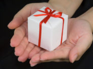 Hands holding a gift box isolated on black background