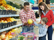 woman with man and child choosing melon fruit during shopping at vegetable supermarket