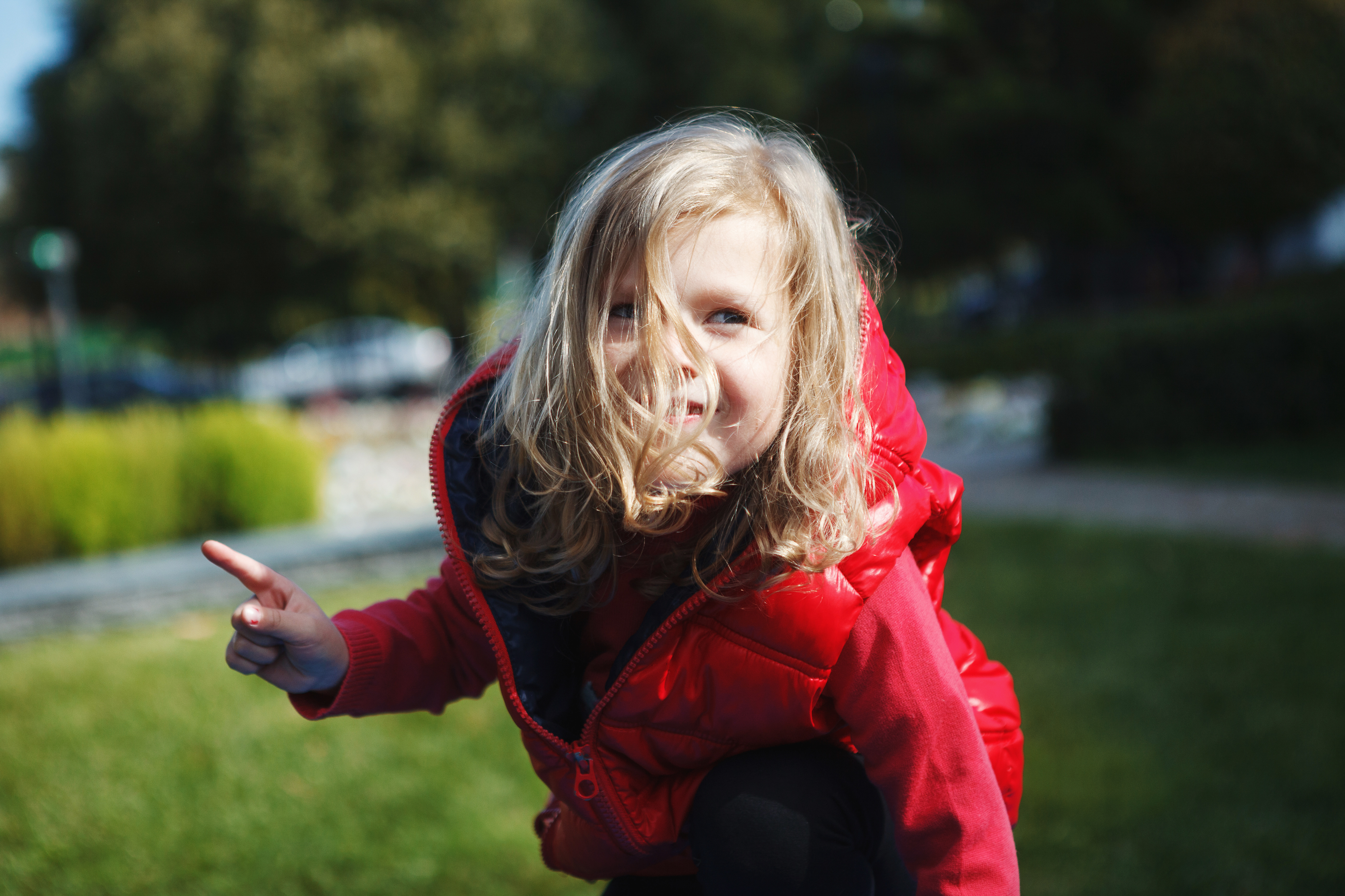 Adorable little child, blonde toddler girl in a red jacket, playing in the autumn Park on the Playground