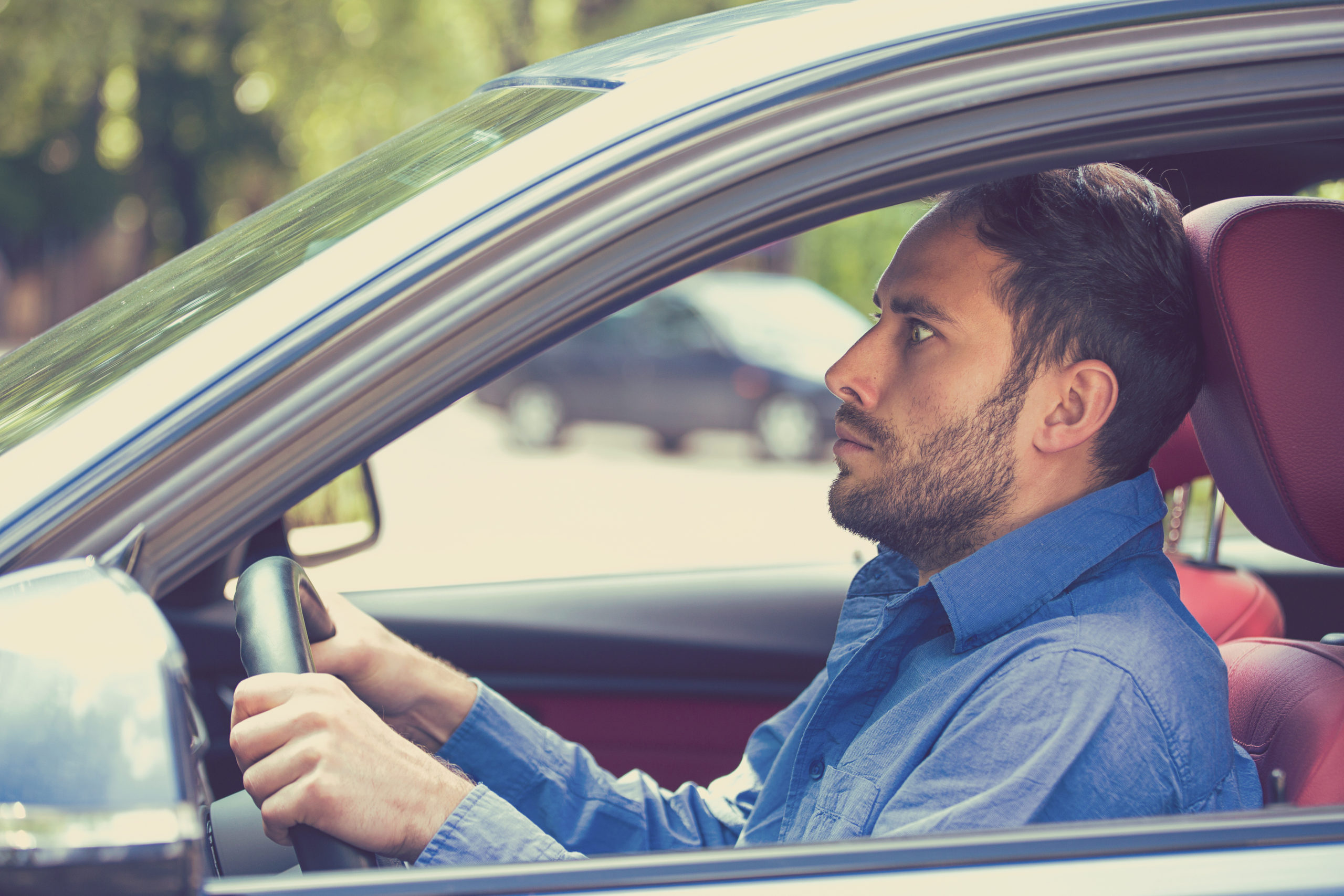 scared funny looking young man driver in the car. Human emotion face expression. Side window view of inexperienced anxious motorist